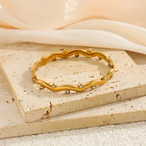 Vue détaillée d'un bracelet jonc vague en acier doré orné de zircons scintillants