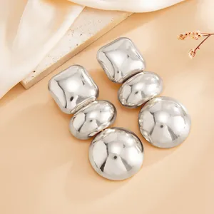 Macro view showing the silver mirror finish of these geometric triple-tiered earrings