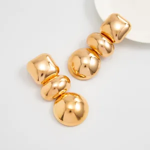 Chunky gold geometric stud earrings with a high-shine mirror finish, close-up detail.