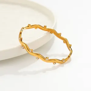 Gros plan d'un bracelet jonc ondulé en acier inoxydable doré avec zircons cubiques