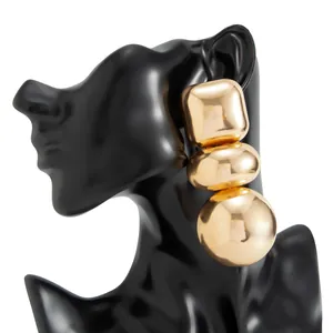 Detailed macro shot of bold geometric gold mirror earrings on a black display stand