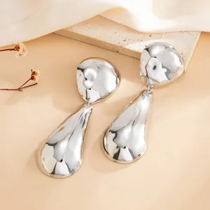 Detailed view of silver-toned drop earrings with irregular hammered mirror finish