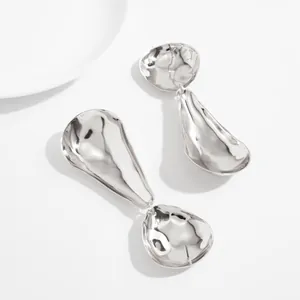 Close-up of oversized geometric earrings with silver mirror finish and water drop design