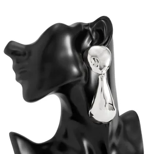 Close-up of oversized silver teardrop earrings with a polished mirror finish on mannequin
