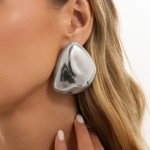 Close-up detail of silver chunky teardrop stud earring with mirror finish on model