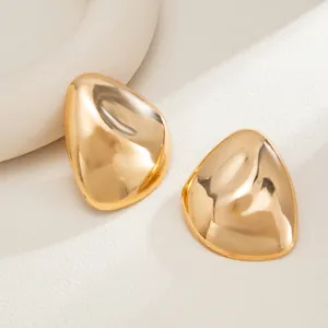 Close-up of chunky gold geometric waterdrop stud earrings with a mirror finish