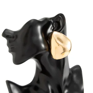 Macro view of chunky gold teardrop stud earring with a glossy mirror finish on model.