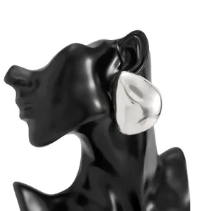 Macro view of oversized silver teardrop mirror stud earring on black mannequin stand.