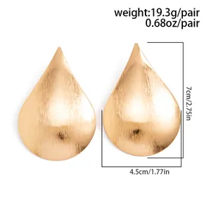 Large teardrop-shaped gold stud earrings with a brushed metallic finish detail view