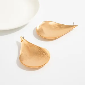 Close-up of gold waterdrop geometric stud earrings with brushed metallic texture.