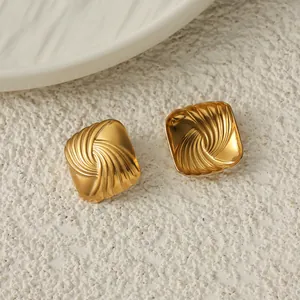 Primo piano di orecchini a bottone quadrati in acciaio dorato con texture a spirale