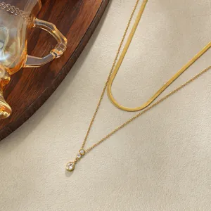 Dettaglio di una collana a strati placcata oro 18 carati con ciondolo in zirconia a goccia.