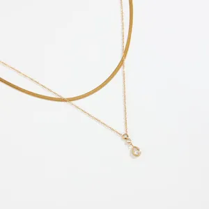 Dettaglio della collana dorata a strati con catena a serpente e pendente in zircone