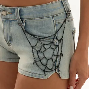 Close-up of a gothic black spiderweb chain body accessory displayed on denim shorts