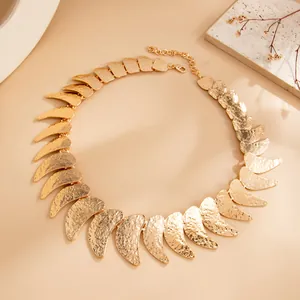 Primer plano detallado de un collar de metal martillado dorado con lunas unidas