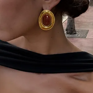 Dettaglio di eleganti orecchini ovali dorati vintage con intarsio in resina ambra