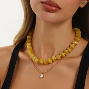 Nahaufnahme einer gelben Harzperlenkette mit einem goldenen Zirkonia-Anhänger.