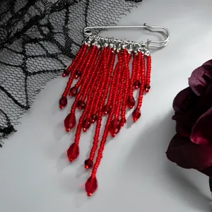 Vue détaillée de pampilles en cristal rouge et petites perles sur une broche argentée