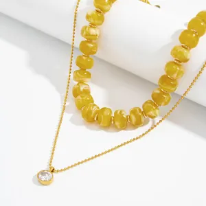 Nahaufnahme der geschichteten Harzperlenkette und Goldkette mit Zirkonia.