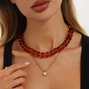 Detailansicht einer bernsteinfarbenen Harzperlenkette mit Zirkonia-Anhänger aus Gold.
