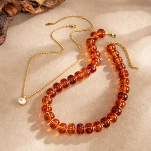 Nahaufnahme der Bernsteinfarben-Resin-Halskette und Goldkette mit Zirkonia-Anhänger.