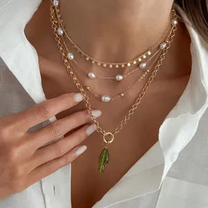 Gros plan d'un collier doré à plusieurs rangs avec perles et pendentif poisson vert
