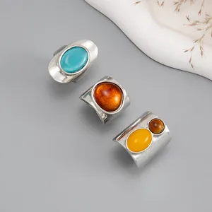 Detail view of three vintage silver rings with colorful resin stones on grey background