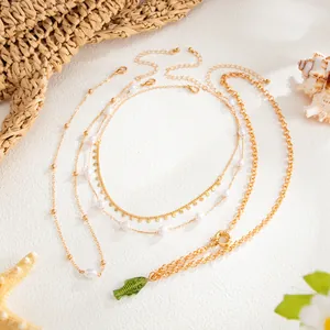Détail du collier multi-rangs doré avec perles et pendentif poisson en verre vert.