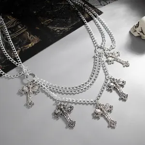 Close-up detail of ornate gothic cross pendants on a multi-layered silver body chain