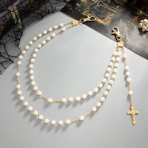 Detail of faux pearl double-layered pants chain with gold cross pendant in gothic style.