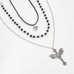 Gothic layered necklace set with skull and crucifix moth wing pendants on white background.