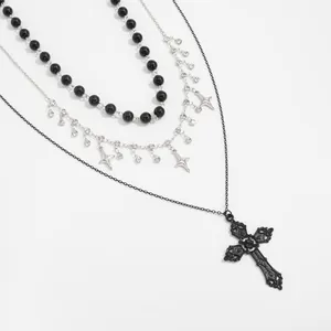 Detail of three-layer Gothic necklace featuring black beads, star charms and cross.