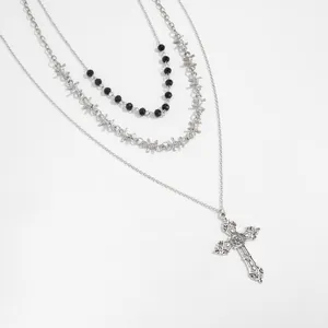 Detailed view of multi-layer gothic necklace with cross pendant and barbed wire chain.