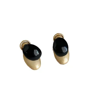 Elegantes pendientes de botón ovales con esmalte negro y acabado metálico dorado