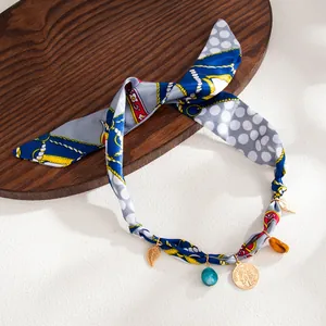 Detailed macro view of bohemian style printed silk scarf necklace with resin charms