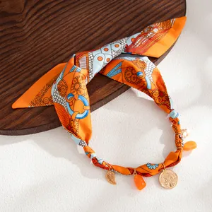 Detailed view of bohemian silk scarf necklace with orange resin and gold coin charms