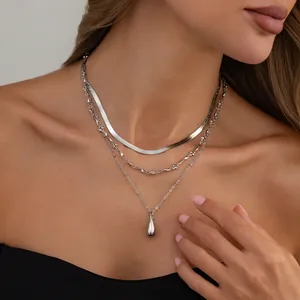 Détail d'un collier argenté à trois couches avec un pendentif en forme de goutte d'eau