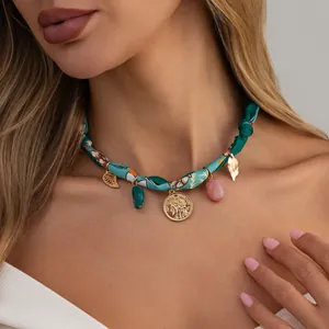 Close-up of Bohemian printed silk scarf necklace with leaf and coin charms on model
