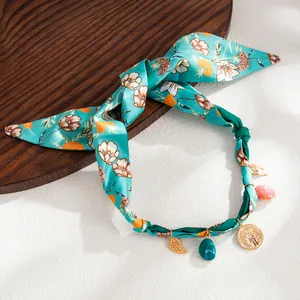 Detail view of Bohemian floral silk scarf necklace with gold charms and resin pendants