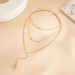 Vue détaillée du collier doré multicouches élégant avec pendentif goutte d'eau sous lumière chaude