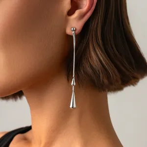 Nahaufnahme eines eleganten silbernen Quastenohrrings mit einem Wassertropfenanhänger