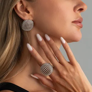 Primo piano di anello e orecchini a sfera in maglia metallica argentata su modella