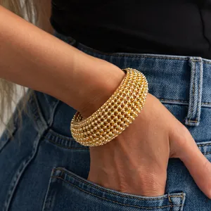 Primo piano dettagliato di un bracciale rigido dorato a maglia intrecciata sul polso
