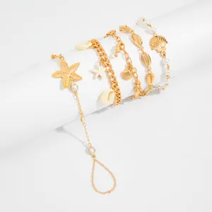 Detalle de conjunto de pulseras doradas de estilo marino con estrellas de mar.