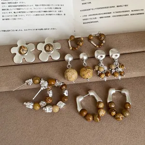 Gedetailleerde weergave van diverse retro metalen oorbellen met bruine natuurstenen.