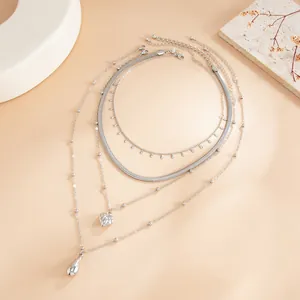 Détail du collier argenté multicouche avec pendentifs en cœur et goutte d'eau