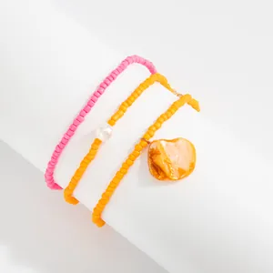Detailed view of bohemian seed bead anklets with pink, yellow beads and shell pendant