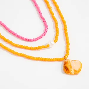Detail shot of colorful Bohemian seed bead anklets featuring a large orange shell pendant