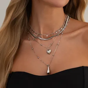 Ensemble élégant de colliers argentés multi-rangs avec pendentifs cœur et goutte d'eau sur modèle