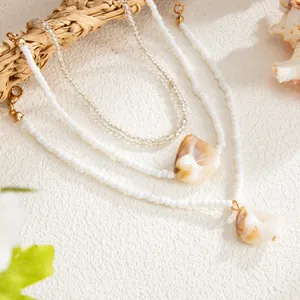 Detailed macro view of Bohemian white seed bead anklets featuring natural shell pendants.